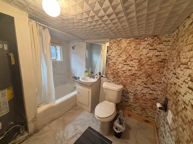 full bathroom featuring shower / bathtub combination with curtain, vanity, gas water heater, and toilet