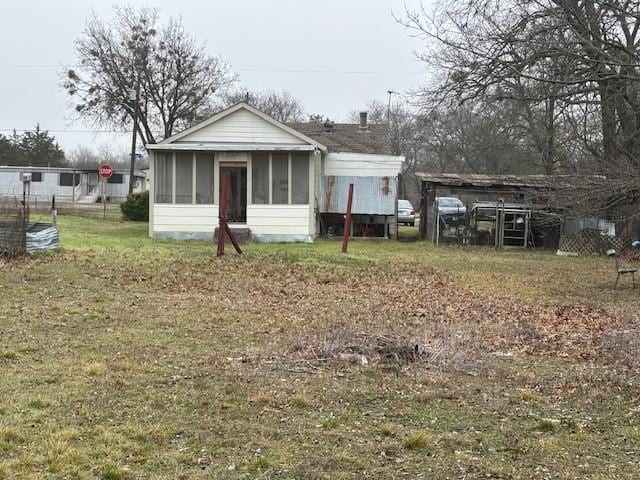 back of property featuring a lawn and a sunroom