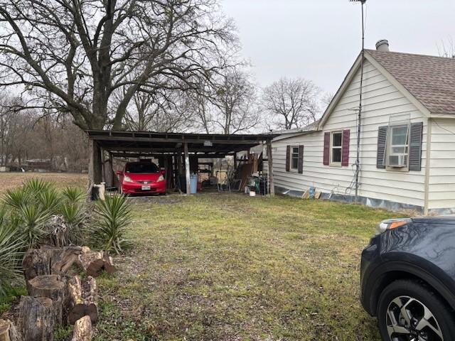 view of side of property featuring cooling unit, a yard, and a carport