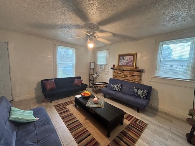 living room featuring ceiling fan, plenty of natural light, light hardwood / wood-style flooring, and a textured ceiling