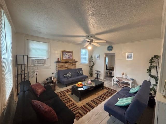 living room with cooling unit, ceiling fan, wood-type flooring, and a textured ceiling