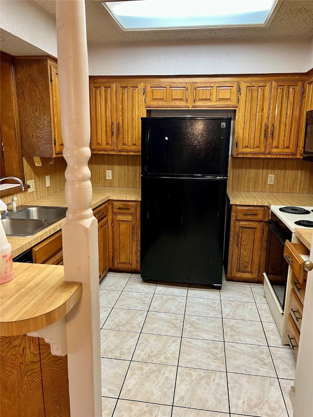 kitchen with sink, light tile patterned floors, and black appliances