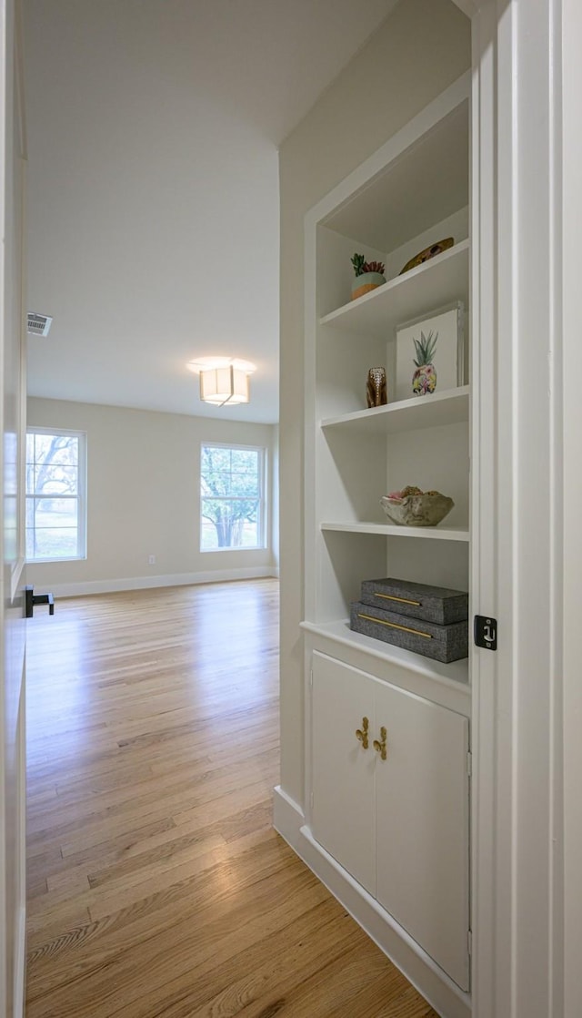 hall featuring built in features and light wood-type flooring