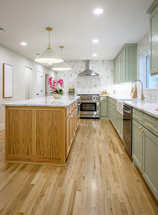 kitchen with dishwasher, a kitchen island, stainless steel range, and wall chimney exhaust hood