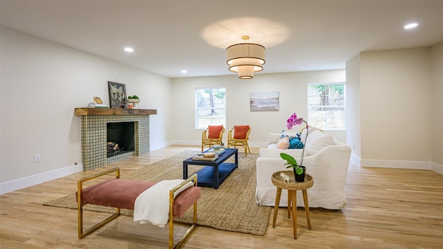 living room with light hardwood / wood-style flooring, a tiled fireplace, and plenty of natural light