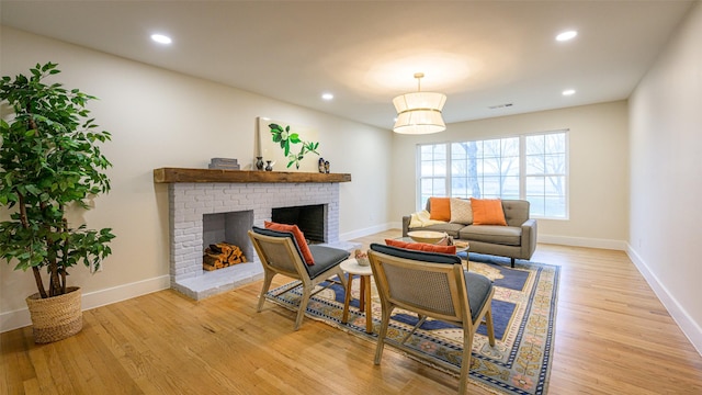 living room with a brick fireplace and light wood-type flooring