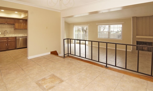 tiled empty room featuring sink, ornamental molding, a raised ceiling, and a brick fireplace