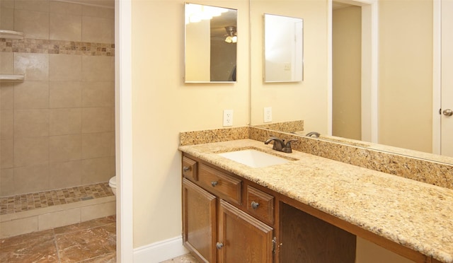 bathroom featuring vanity, tiled shower, and toilet