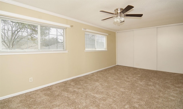 carpeted empty room with ceiling fan, ornamental molding, and a textured ceiling