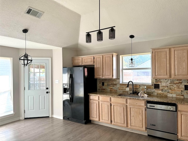 kitchen featuring light brown cabinetry, sink, black fridge, stainless steel dishwasher, and pendant lighting