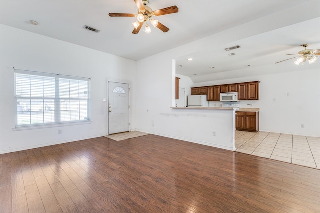 unfurnished living room with light wood-style floors, visible vents, ceiling fan, and baseboards