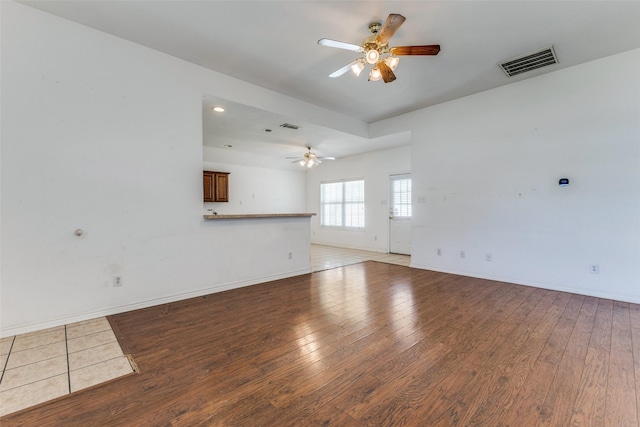 unfurnished living room featuring light wood-style floors, baseboards, visible vents, and a ceiling fan