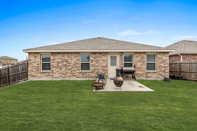 rear view of house featuring a patio area, a fenced backyard, brick siding, and a yard