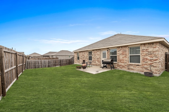 rear view of house featuring a patio, a fenced backyard, roof with shingles, a yard, and brick siding