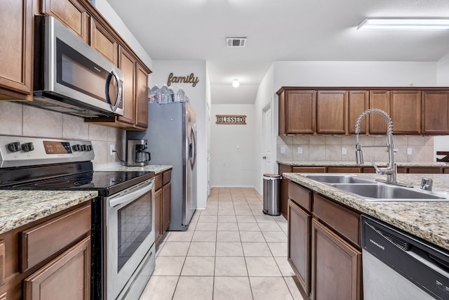 kitchen featuring stainless steel appliances, light tile patterned flooring, sink, and backsplash