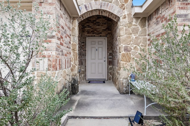 doorway to property featuring stone siding and brick siding