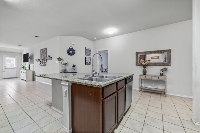 kitchen with sink, light tile patterned floors, dishwasher, light stone counters, and a center island with sink