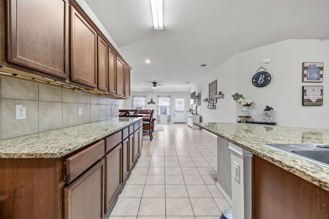 kitchen with light stone counters, light tile patterned floors, decorative backsplash, and ceiling fan