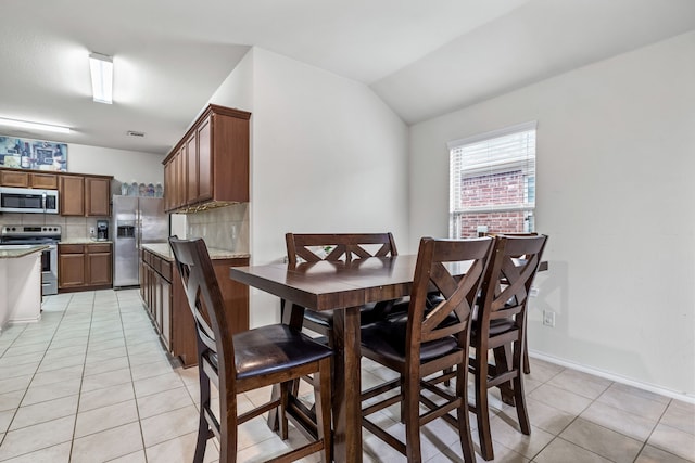 tiled dining area featuring vaulted ceiling