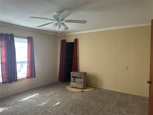 empty room featuring crown molding, a textured ceiling, a wood stove, ceiling fan, and carpet