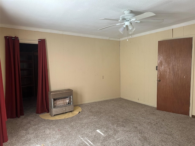 carpeted spare room featuring crown molding, a wood stove, heating unit, and ceiling fan