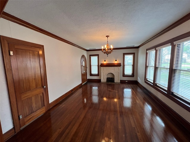 unfurnished living room with an inviting chandelier, a fireplace, dark hardwood / wood-style flooring, crown molding, and a textured ceiling