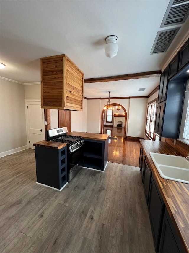 kitchen with ornamental molding, stainless steel range with gas cooktop, sink, and wooden counters