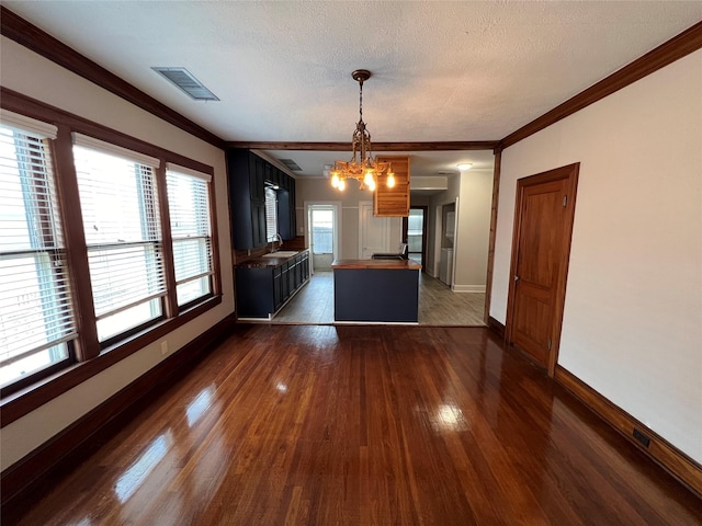 interior space featuring dark wood-type flooring, sink, crown molding, a chandelier, and a textured ceiling