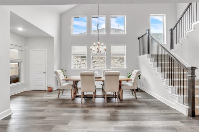 dining room featuring a notable chandelier, hardwood / wood-style flooring, and a towering ceiling