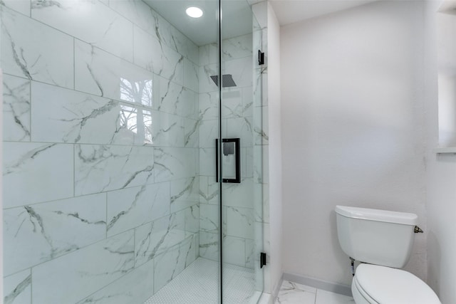 bathroom featuring a shower with shower door and toilet