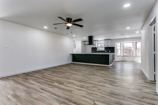 unfurnished living room with wood-type flooring and ceiling fan