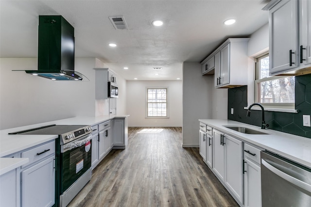 kitchen featuring sink, extractor fan, tasteful backsplash, light hardwood / wood-style flooring, and appliances with stainless steel finishes