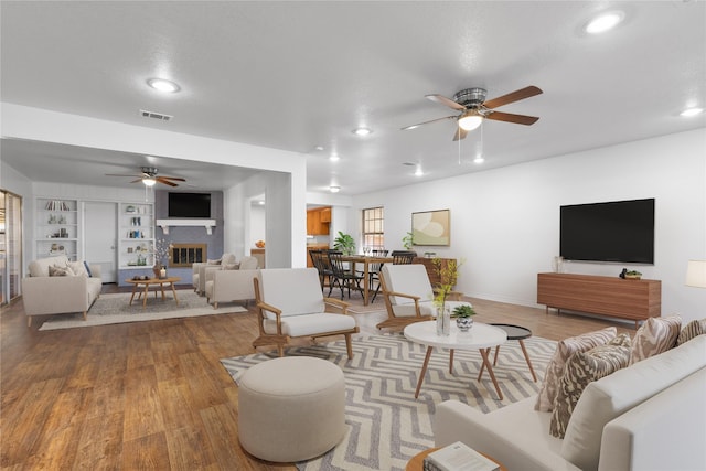 living room with hardwood / wood-style floors, built in features, and ceiling fan