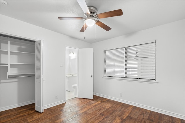 unfurnished bedroom with dark wood-type flooring, ceiling fan, connected bathroom, and a closet