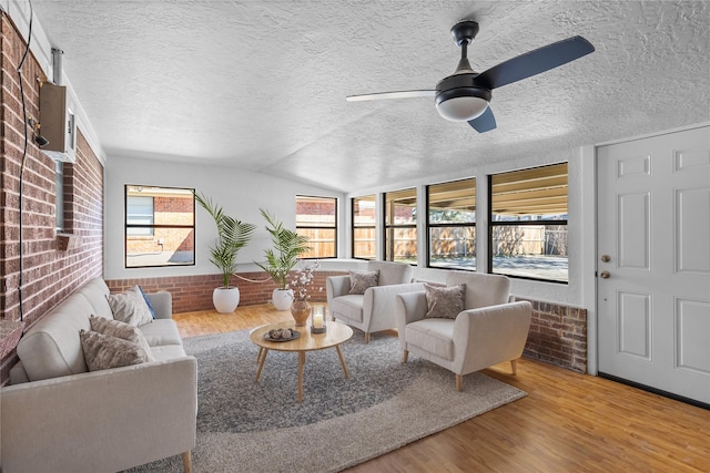 living room with hardwood / wood-style flooring, brick wall, and a wealth of natural light