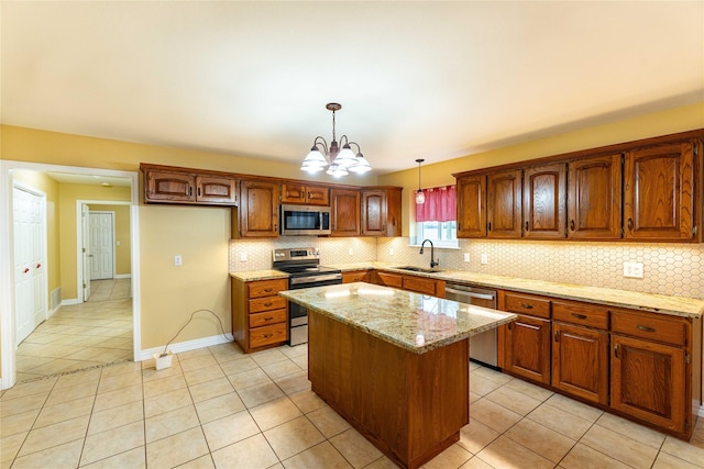 kitchen featuring sink, appliances with stainless steel finishes, hanging light fixtures, light stone countertops, and a kitchen island