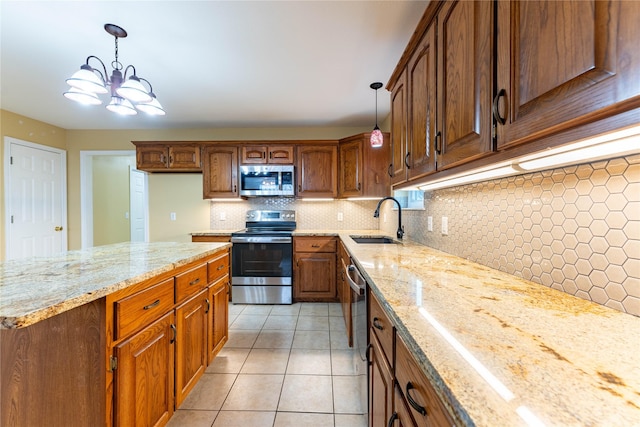 kitchen with appliances with stainless steel finishes, sink, pendant lighting, and light stone counters