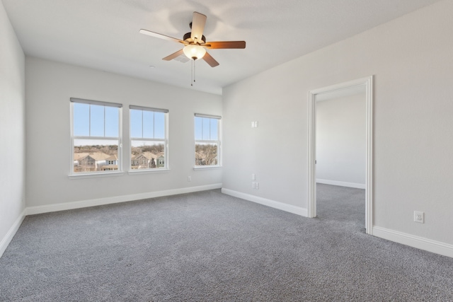 carpeted empty room with ceiling fan and baseboards