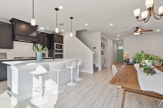 kitchen with light wood finished floors, stainless steel appliances, light countertops, visible vents, and decorative backsplash