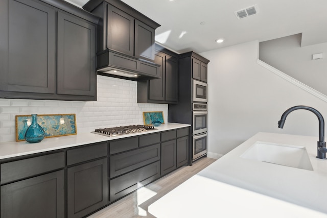 kitchen featuring stainless steel appliances, light countertops, visible vents, backsplash, and a sink