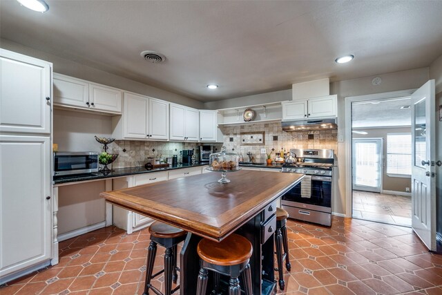 kitchen with visible vents, backsplash, wooden counters, appliances with stainless steel finishes, and white cabinetry