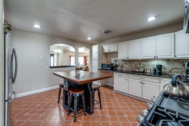 kitchen featuring tile patterned flooring, visible vents, arched walkways, and appliances with stainless steel finishes