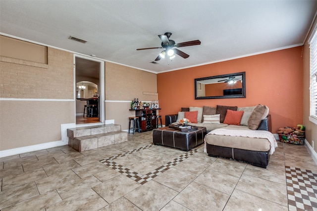 living area with visible vents, baseboards, a ceiling fan, and crown molding