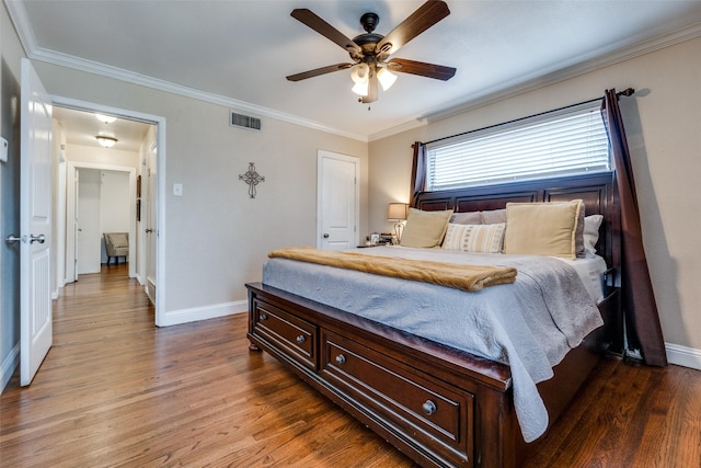 bedroom featuring baseboards, wood finished floors, visible vents, and ornamental molding