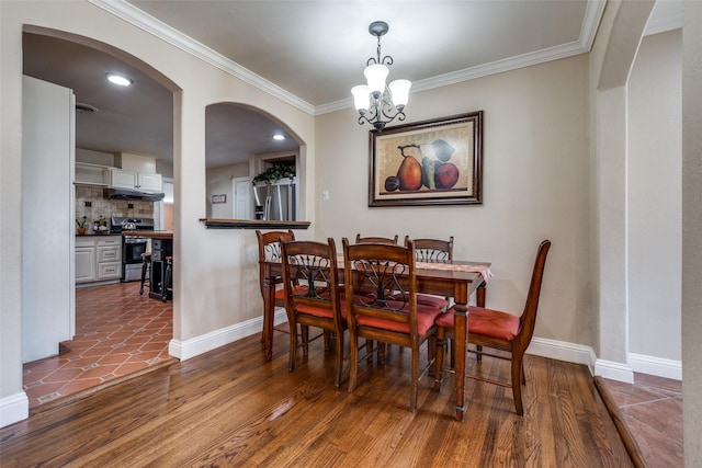 dining area with an inviting chandelier, wood finished floors, baseboards, and ornamental molding