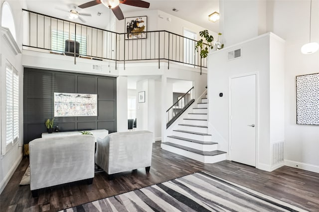 living room with ceiling fan, dark hardwood / wood-style floors, and a high ceiling