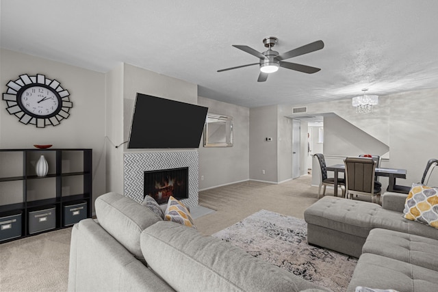 living room featuring a textured ceiling, light carpet, a tile fireplace, and ceiling fan with notable chandelier