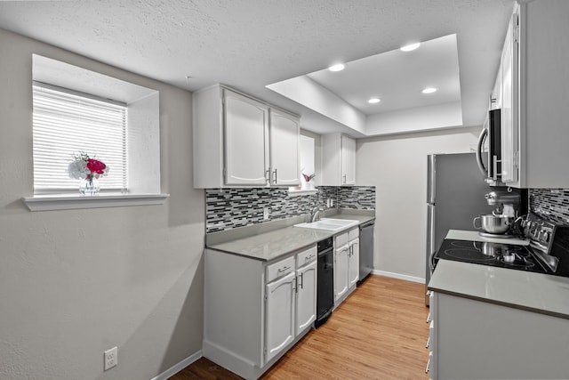 kitchen featuring light hardwood / wood-style flooring, stainless steel appliances, white cabinets, decorative backsplash, and sink