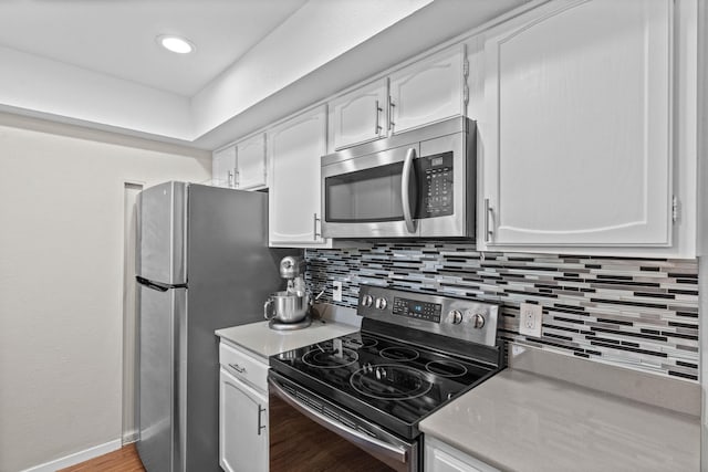 kitchen with white cabinets, tasteful backsplash, stainless steel appliances, and light hardwood / wood-style floors