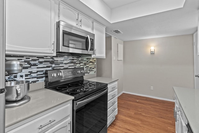 kitchen with light wood-type flooring, white cabinets, range with electric stovetop, and decorative backsplash